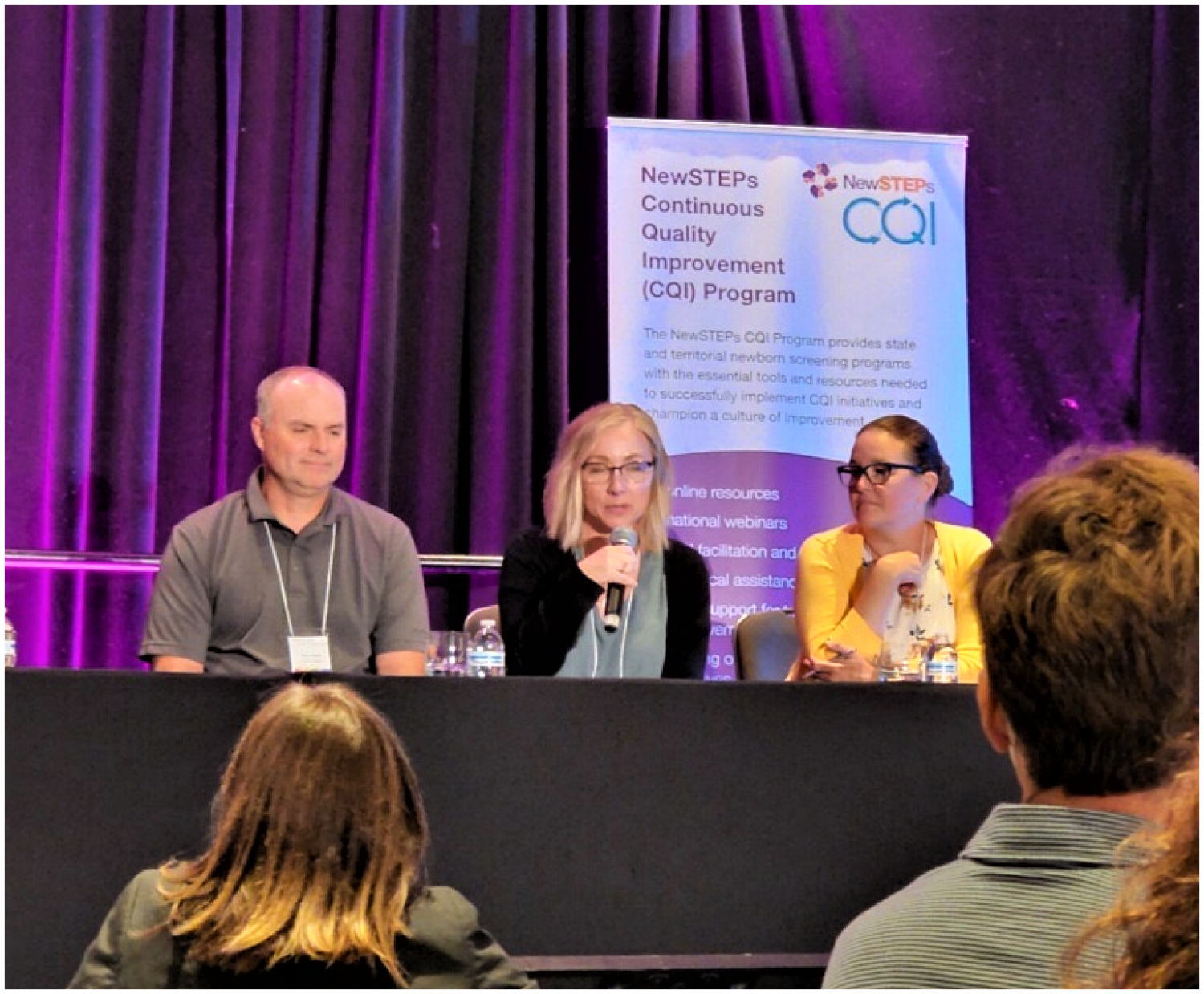 Three Newborn Screening staff answering questions at the conference.